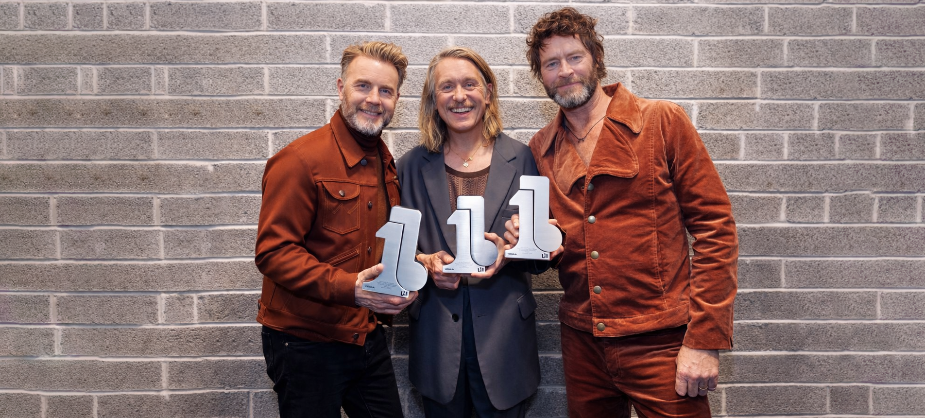 Take That holding bespoke sculptural acrylic awards with modern number design by Midton