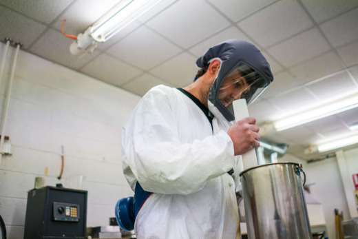 cast acrylic technician mixing cast acrylic in a metal container using a plastic stick