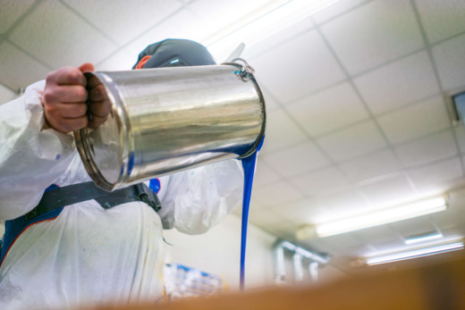 Casting technician pouring acrylic mix in metal moulds for acrylic fabrication