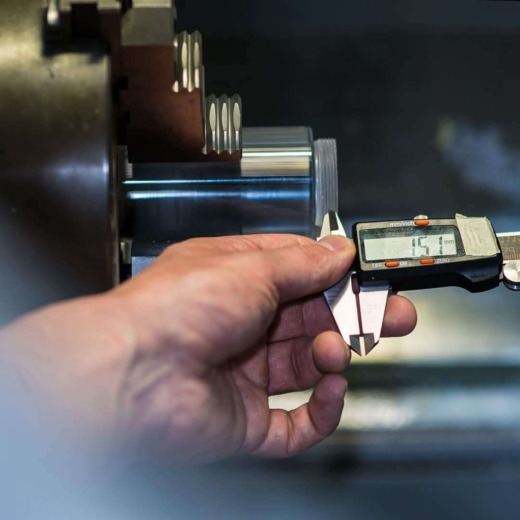 Measuring tool and hand on an lather with clear acrylic cylinder with thread for acrylic fabrication