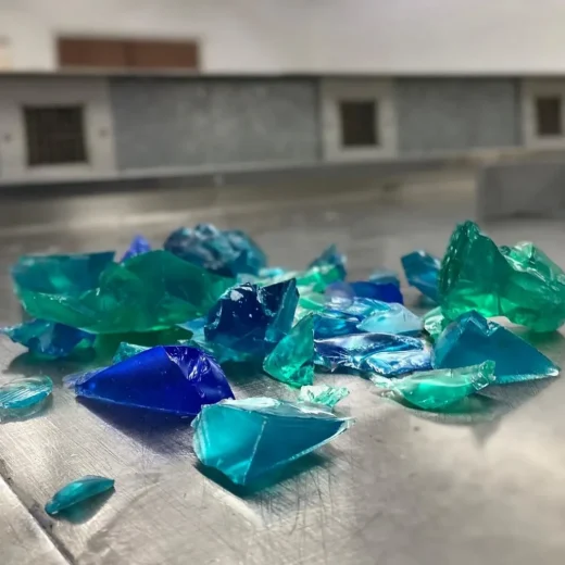 Translucent green and blue coloured acrylic shards on a metal bench to be used for custom materials