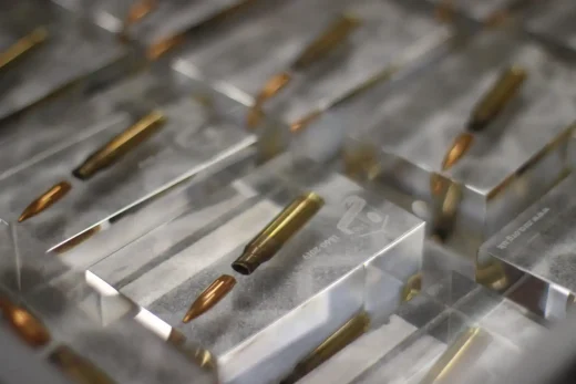 Clear acrylic commemorative gifts with bullets embedded, eight lying on a table.