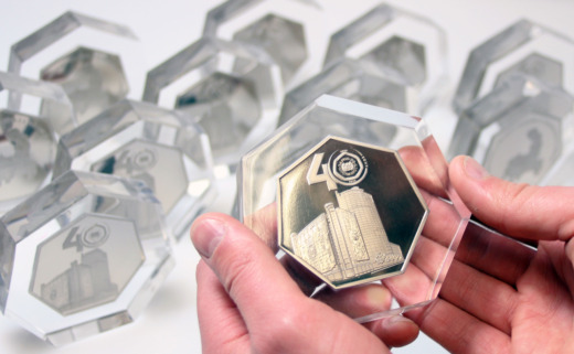Clear acrylic commemorative gifts with silver coin embedded being held in two hands