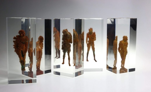 Five brown textured figurines embedded in clear acrylic Columns for movie props