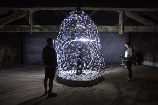 Two men standing next to a dome shaped lighting display with small acrylic shards for movie props