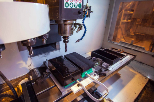 CNC machine with black acrylic rectangle product displays ready to be machined to shape