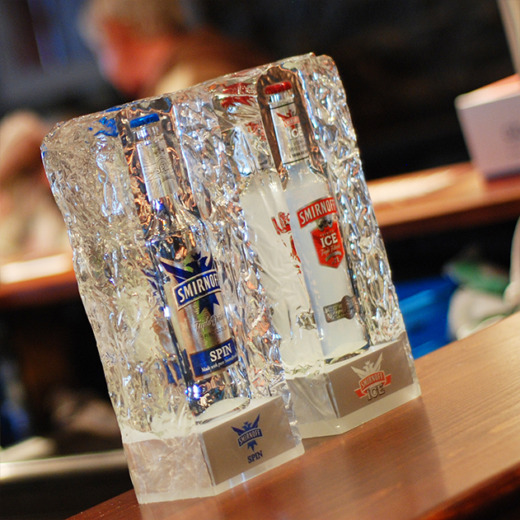 Two Smirnoff Ice bottles embedded in a clear acrylic ice block mounted to a pub bar