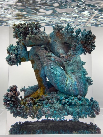 Sculpture art figure sitting with one knee up embedded in clear acrylic with a wave textured top for movie props