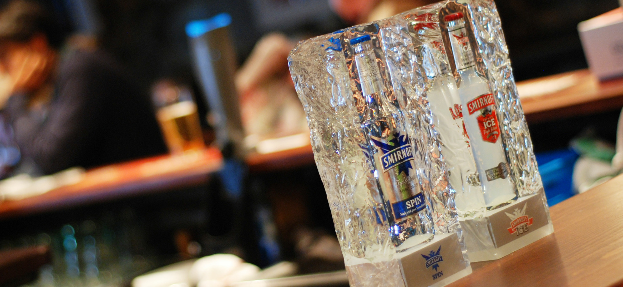 Smirnoff Ice bottle glorifiers with bottles embedded in clear acrylic ice effect blocks on a bar top