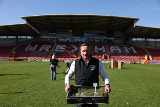 Midton director collecting Wrexham AFC pitch turf at the Racecourse Ground for football memorabilia fan gifts