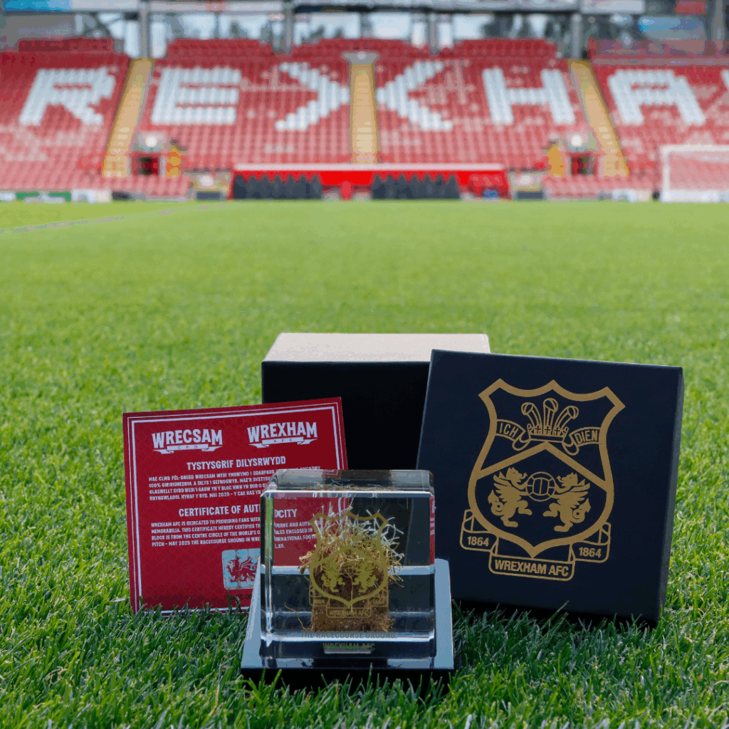 Wrexham AFC limited edition turf cube with certificate of authenticity and black and gold gift box, showcased on the pitch grass.