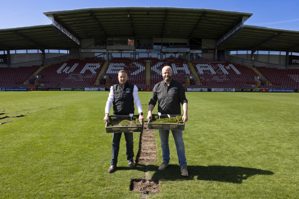 Midton directors collecting sections of turf from the Wrexham AFC pitch at the STōK Cae Ras for use in fan merchandise.