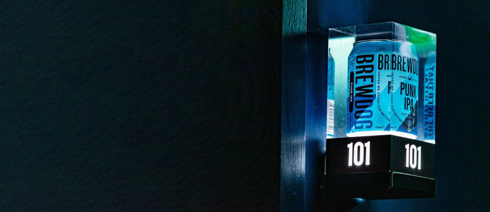 Close-up of BrewDog Punk IPA beer can embedded in crystal clear acrylic block with illuminated hotel room number signage produced by Midton.