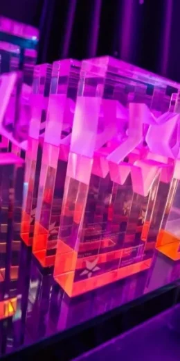 Colourful bespoke acrylic awards displayed at event with illuminated finish